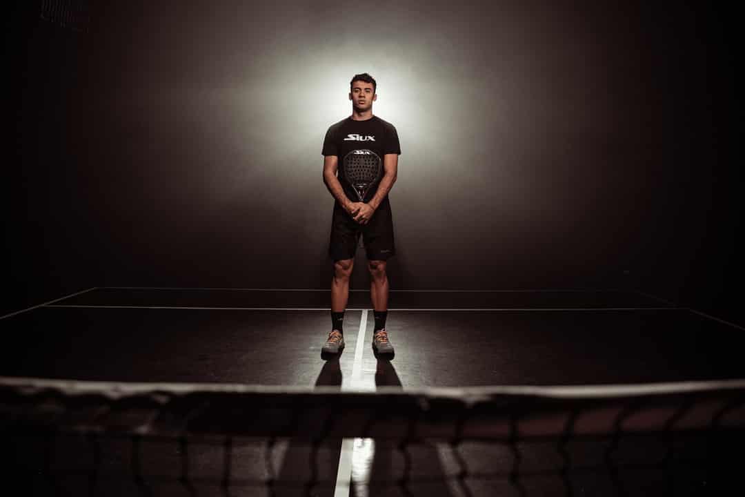 Leo Augsburger poseert op een padelbaan in Siux-kleding met zijn signature racket