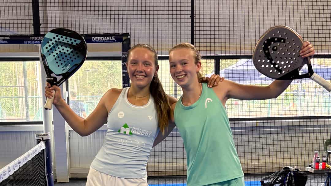 Twee jeugdspeelsters vieren hun titel met opgeheven padelrackets op de baan in Mol