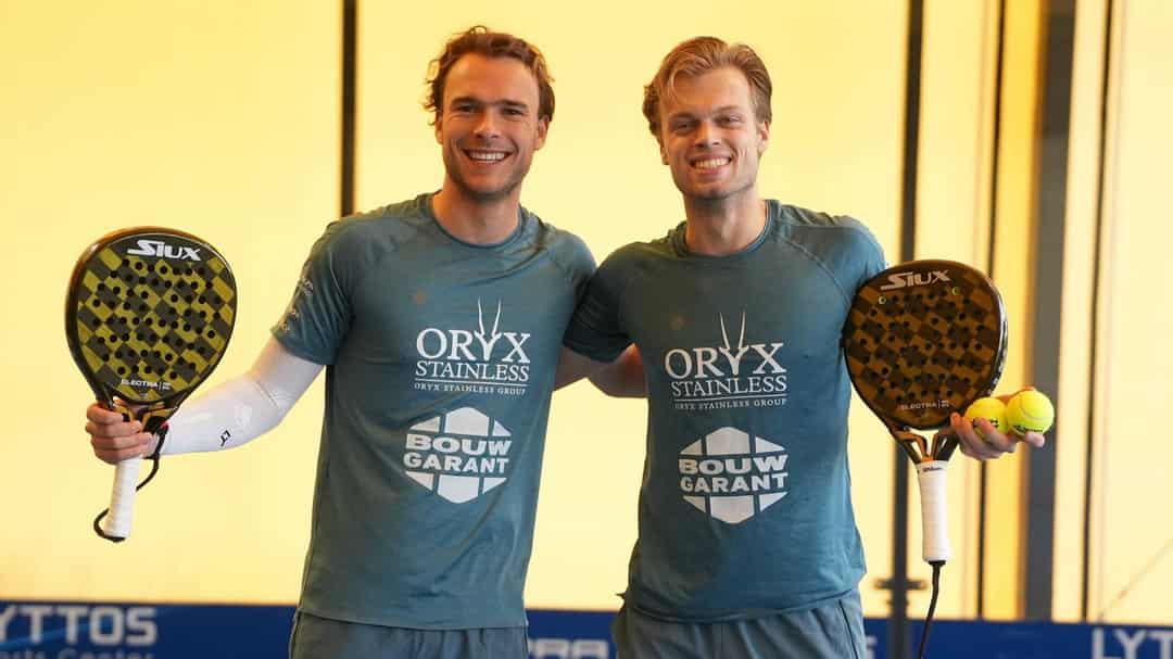 Julian Prins en Youp de Kroon poseren lachend met hun rackets op de padelbaan