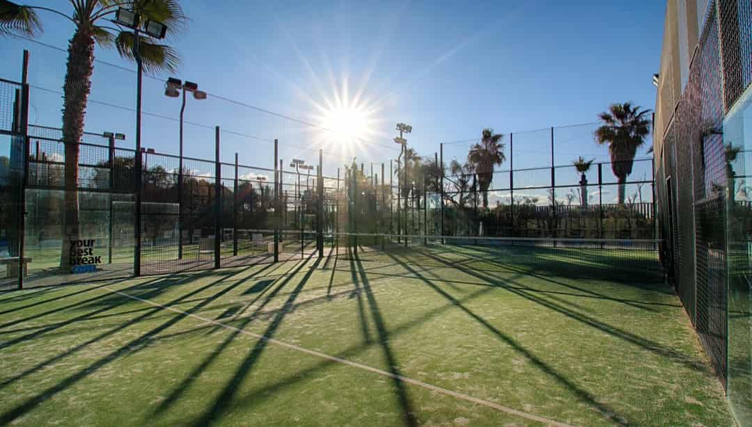 Outdoor padelbanen in de zon bij een David Lloyd-club met palmbomen op de achtergrond