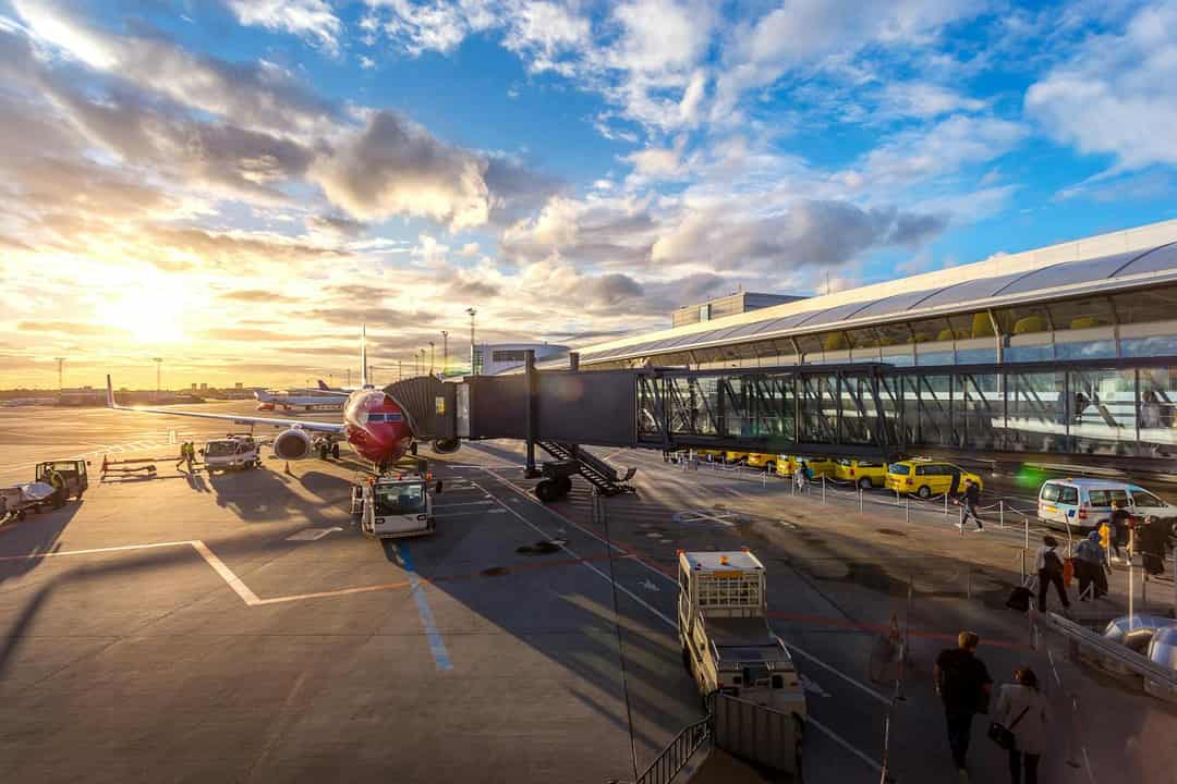Vliegtuig aan de gate op een luchthaven bij zonsondergang — padelspelers gestrand door vluchtverstoringen
