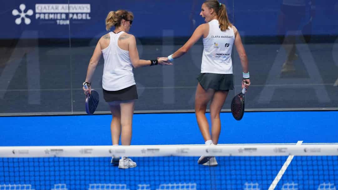 Twee speelsters geven elkaar een hand aan het net op de blauwe baan tijdens de vrouwenkwalificatie van het Alpine Paris Major