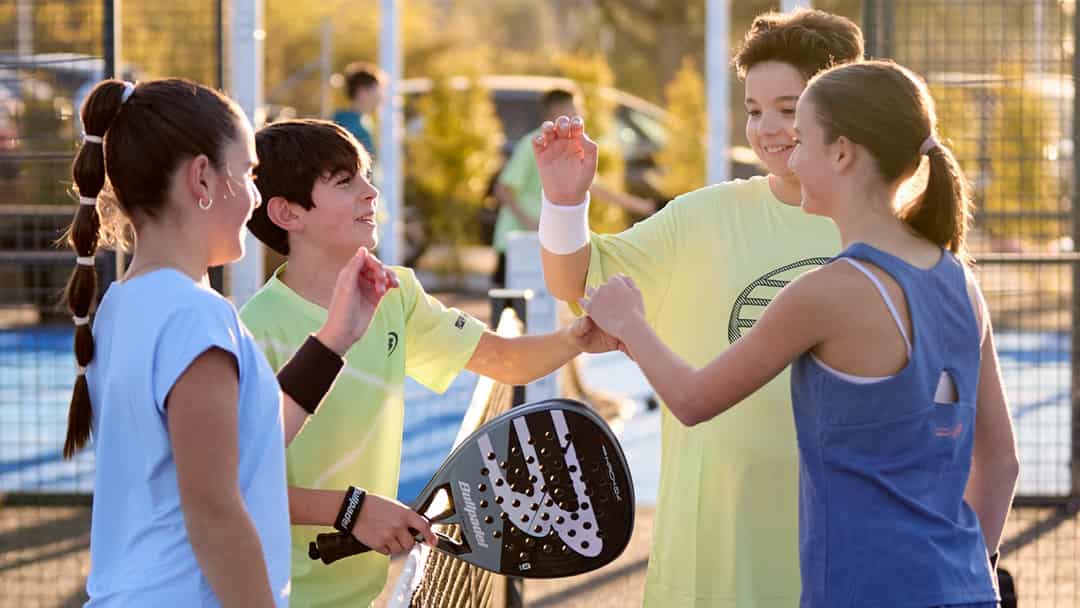 Jonge padelspelers geven elkaar een fist bump op een outdoor padelbaan tijdens een training
