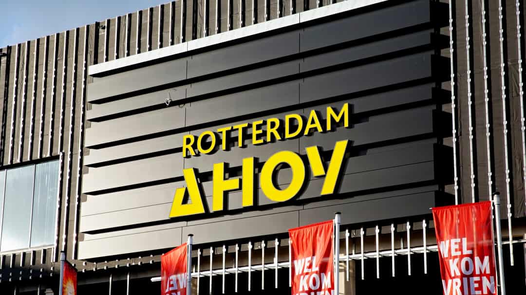 De gevel van Rotterdam Ahoy met het gele logo en welkomstvlaggen